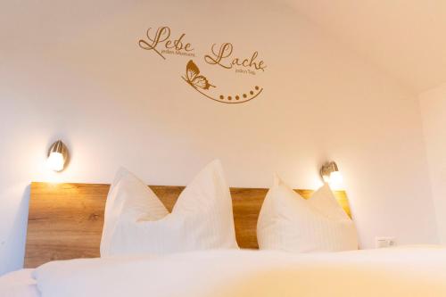 a bedroom with a bed with white pillows and a sign on the wall at Hotel Bergidyll in Pfronten