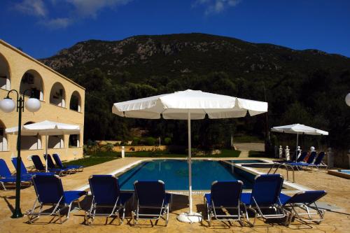 Ágios Matthaíos的住宿－Prasoudopetra，一座带椅子和遮阳伞的游泳池位于大楼旁