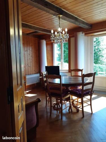 une salle à manger avec une table et des chaises en bois dans l'établissement Gîte La petite maison horlogère jacuzzi & sauna, à Les Fontenelles