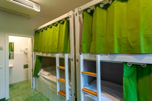 two bunk beds in a room with green curtains at El Albergue de Sigüenza in Sigüenza