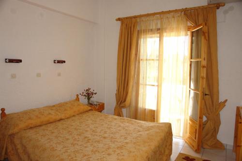 a bedroom with a bed and a large window at Prasoudopetra in Ágios Matthaíos