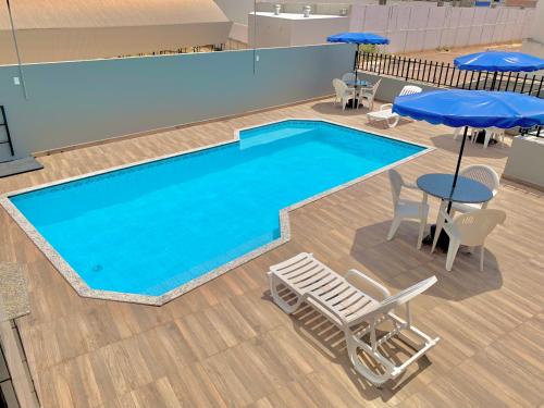 una gran piscina con mesas, sillas y sombrillas en Principe Hotel, en Barreiras
