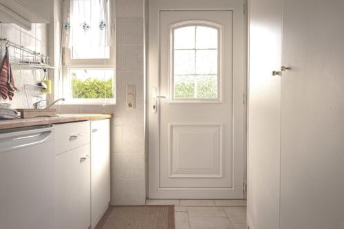 a kitchen with a white door and a window at FeWo Kranich in Fuhlendorf
