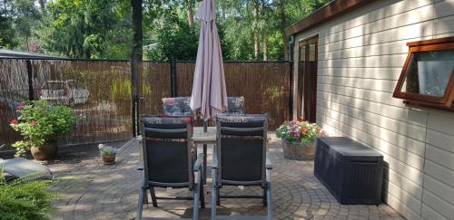 a patio with an umbrella and a table and chairs at Gezellig chalet Doornspijk o11 - Recreation Only in Doornspijk
