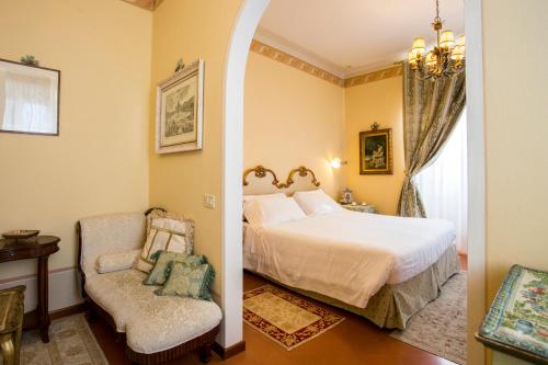 a bedroom with a bed and a chair and a window at Hotel Villa Marsili in Cortona