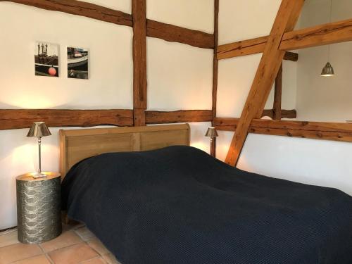 sypialnia z czarnym łóżkiem i drewnianym sufitem w obiekcie Gut Alt Farpen Ferienwohnung 1 w mieście Blowatz