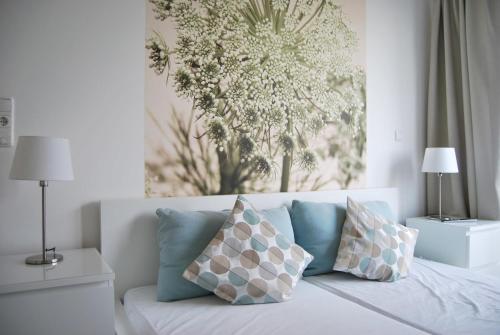 ein weißes Bett mit Kissen und ein Gemälde an der Wand in der Unterkunft Fehmarn-OstseeferienStrandresidenz Vogelflug, App 17 in Fehmarnsund