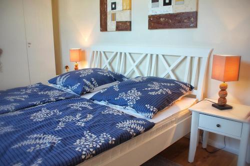 a bed with blue comforter and pillows on it at Strandhafer V4W2 in Dierhagen