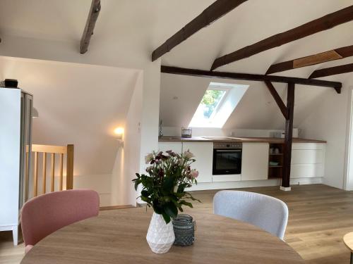 a kitchen with a table with a vase of flowers on it at Loft an der Seefahrtschule - Timmel in Großefehn 