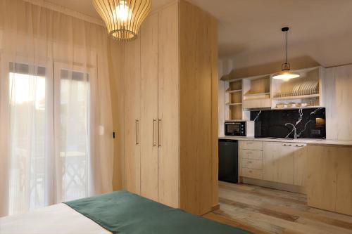普拉塔利亞的住宿－Ares Suites，一个带木制橱柜的厨房和一张位于客房内的床