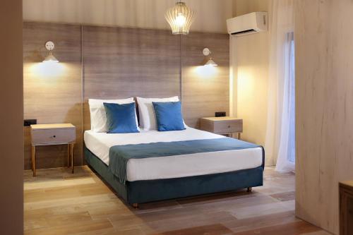1 dormitorio con 1 cama grande con almohadas azules en Ares Suites, en Plataria