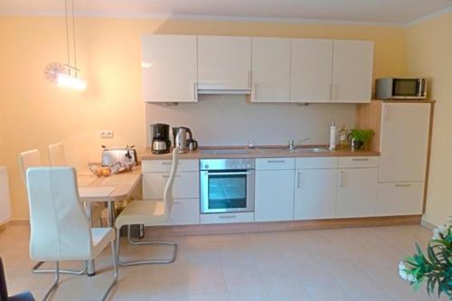 a kitchen with white cabinets and a table with chairs at Strandburg, FW 6 in Zingst