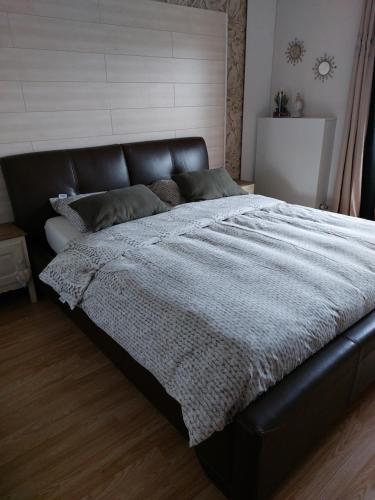 een groot bed met een zwart leren hoofdeinde in een slaapkamer bij De Distel in Oostende