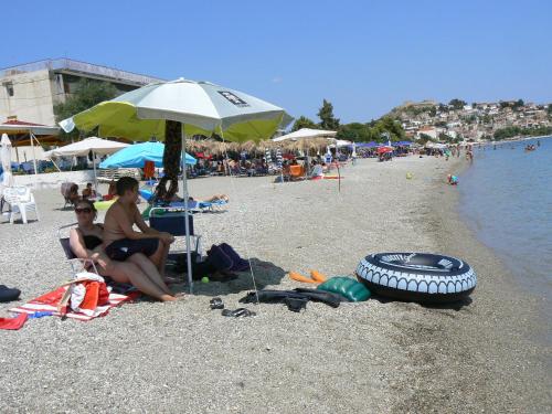 two people sitting under an umbrella on the beach at 85 sqm Apartments New Panorama ELECTRIC CAR ΦΩΡΤΗΣΗΣ STATION in Paralion astros