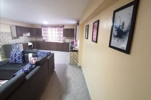 sala de estar con sofá y cocina en Lass Grove Home, en Kisii