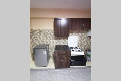 a kitchen with a stove and a trash can at Lass Grove Home in Kisii