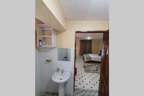 a bathroom with a sink and a room with a bed at Lass Grove Home in Kisii