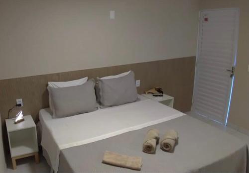 a white bed with two pairs of slippers on it at Pousada Maresia in Fernando de Noronha