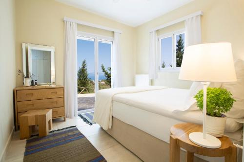 a white bedroom with a bed and a window at Boo Premium Living Villas in Tsoukaladhes