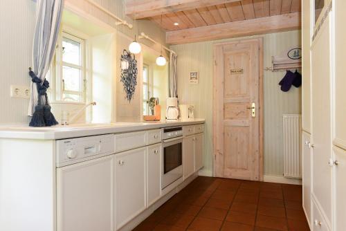 - une cuisine avec des placards blancs, un évier et une porte dans l'établissement Faskers Hüs Whg 01, à Oldsum