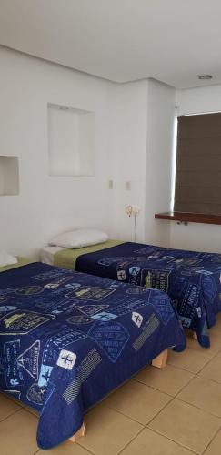 カンクンにあるSuites Moon Riverの青い掛け布団付きの客室内のベッド2台