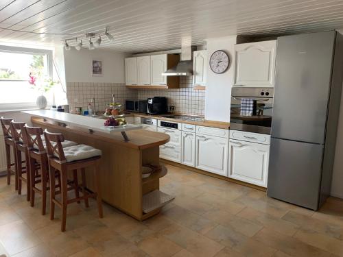 cocina con armarios blancos, nevera y mesa en Allgäu Apartment, en Memmingen