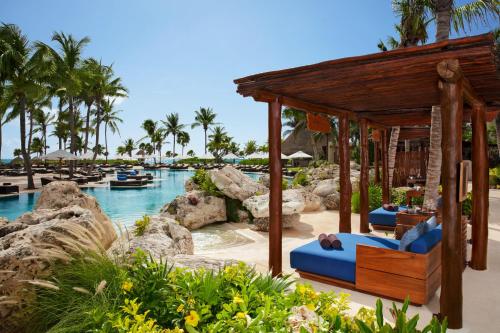 
a beach area with a pool, chairs, and a boat at Secrets Maroma Beach Riviera Cancun - Adults only in Playa del Carmen

