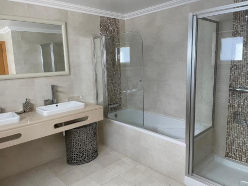 a bathroom with a shower and a sink and a tub at Villa Mar Azul in Albufeira