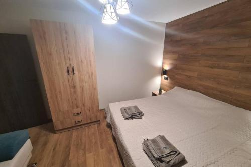 a bedroom with a bed and a wooden headboard at Хотелски апартамент Стило в идеалния център. in Veliko Tŭrnovo
