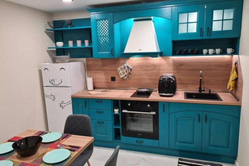 a kitchen with blue cabinets and a table and a refrigerator at Хотелски апартамент Стило в идеалния център. in Veliko Tŭrnovo