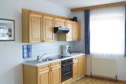a kitchen with wooden cabinets and a sink and a window at Ferienwohnungen Billovits in Kössen