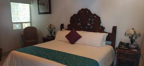 a bedroom with a large bed with a wooden headboard at Posada de Maria Hotel Boutique & Spa in Durango