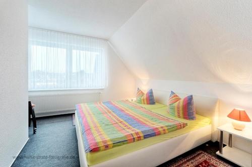 ein Schlafzimmer mit einem Bett mit bunter Decke und einem Fenster in der Unterkunft Wolf, Barbara, FW 3 in Zingst