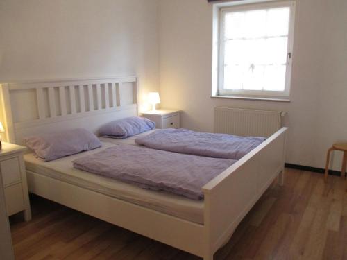 ヴァンガーラントにあるFerienwohnung KRABBE in Hooksielのベッドルーム1室(紫のシーツが敷かれたベッド1台、窓付)