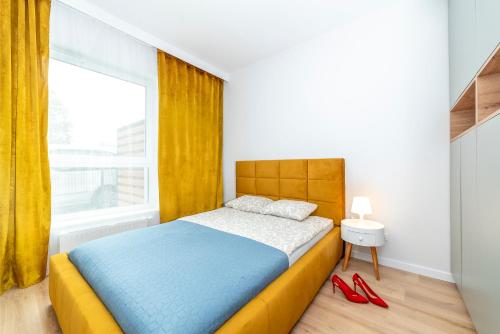 1 dormitorio con cama, ventana y zapatos rojos en Apartamenty Przy IV Śluzie - Gold, en Bydgoszcz
