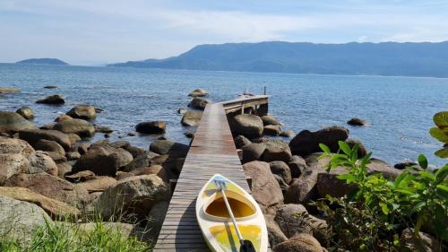a boat sitting on a pier next to the water at Elephant GuestHouse Beira Mar - Suítes com Café da Manhã in Ilhabela