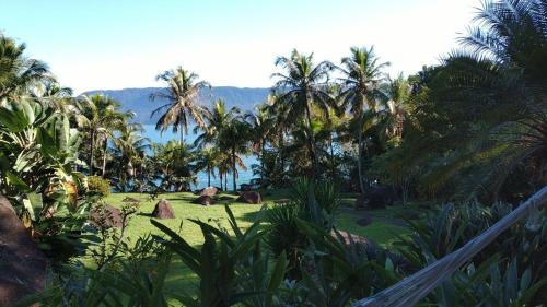 a view of a resort with palm trees and the ocean at Elephant GuestHouse Beira Mar - Suítes com Café da Manhã in Ilhabela