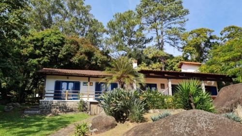 a house with blue doors and trees at Elephant GuestHouse Beira Mar - Suítes com Café da Manhã in Ilhabela