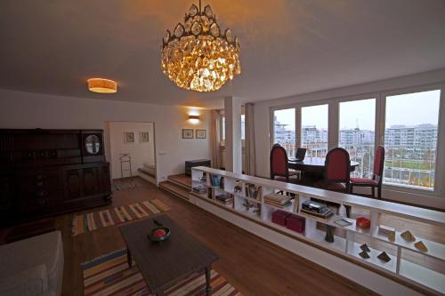 a living room with a chandelier and a room with a table at Arena Penthouse Apartments in Belgrade