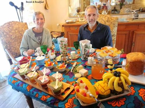 een man en vrouw aan een tafel met eten bij Breizh & Breakfast in Rosporden