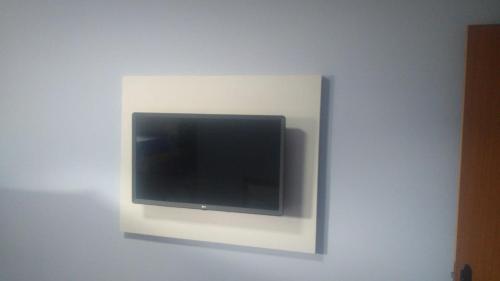 TV de pantalla plana montada en una pared blanca en Pousada da Lagoa, en Arraial do Cabo