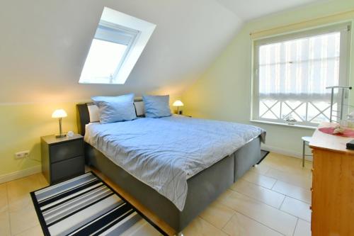 a bedroom with a bed with blue pillows and a window at Min Hüsken in Zingst