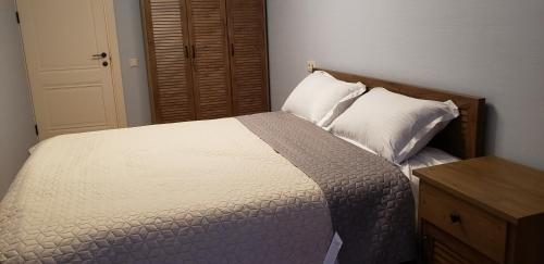 1 dormitorio con cama blanca y cabecero de madera en Apartment - 200 m Near Central Park, en Tiflis