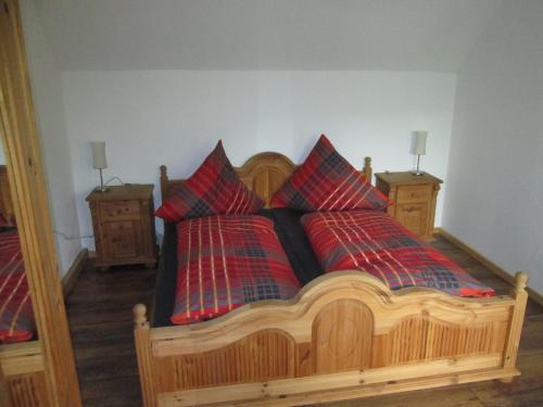 a bedroom with a wooden bed with two red pillows at Eulennest in Carlsberg