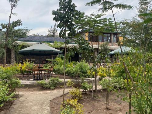 a house with a garden with a table and an umbrella at Oldarpoi Wageni Camps in Keekorok
