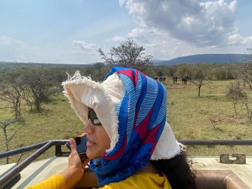 a woman wearing a hat talking on a cell phone at Oldarpoi Wageni Camps in Keekorok