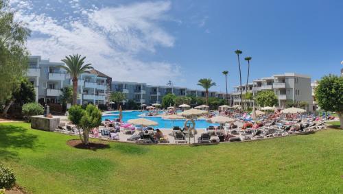 ロス・クリスティアーノスにあるPrivate Apartment 150 HG Tenerife Surのリゾート内のプール(椅子、パラソル付)