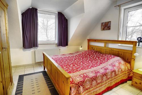 a bedroom with a wooden bed and two windows at Am Strand 4,PP innen in Zingst
