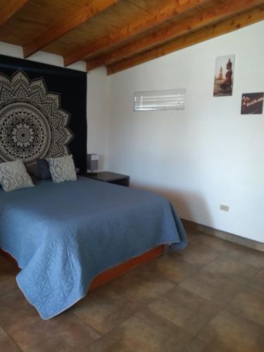 - une chambre avec un lit bleu dans un mur blanc dans l'établissement Posada Soleil Bed & Breakfast, à Valle de Guadalupe
