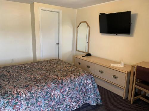 a bedroom with a bed and a dresser with a television at Nitey Nite Motel in South Windsor
